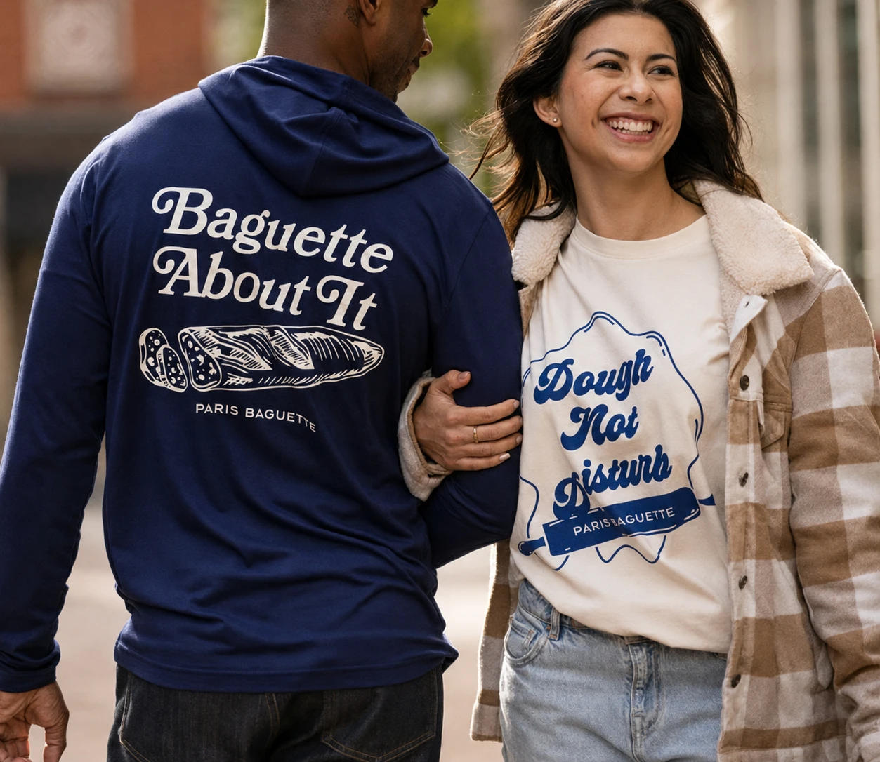 Two people modeling a navy Baguette About It hoodie and a cream Dough Not Disturb graphic T-shirt.