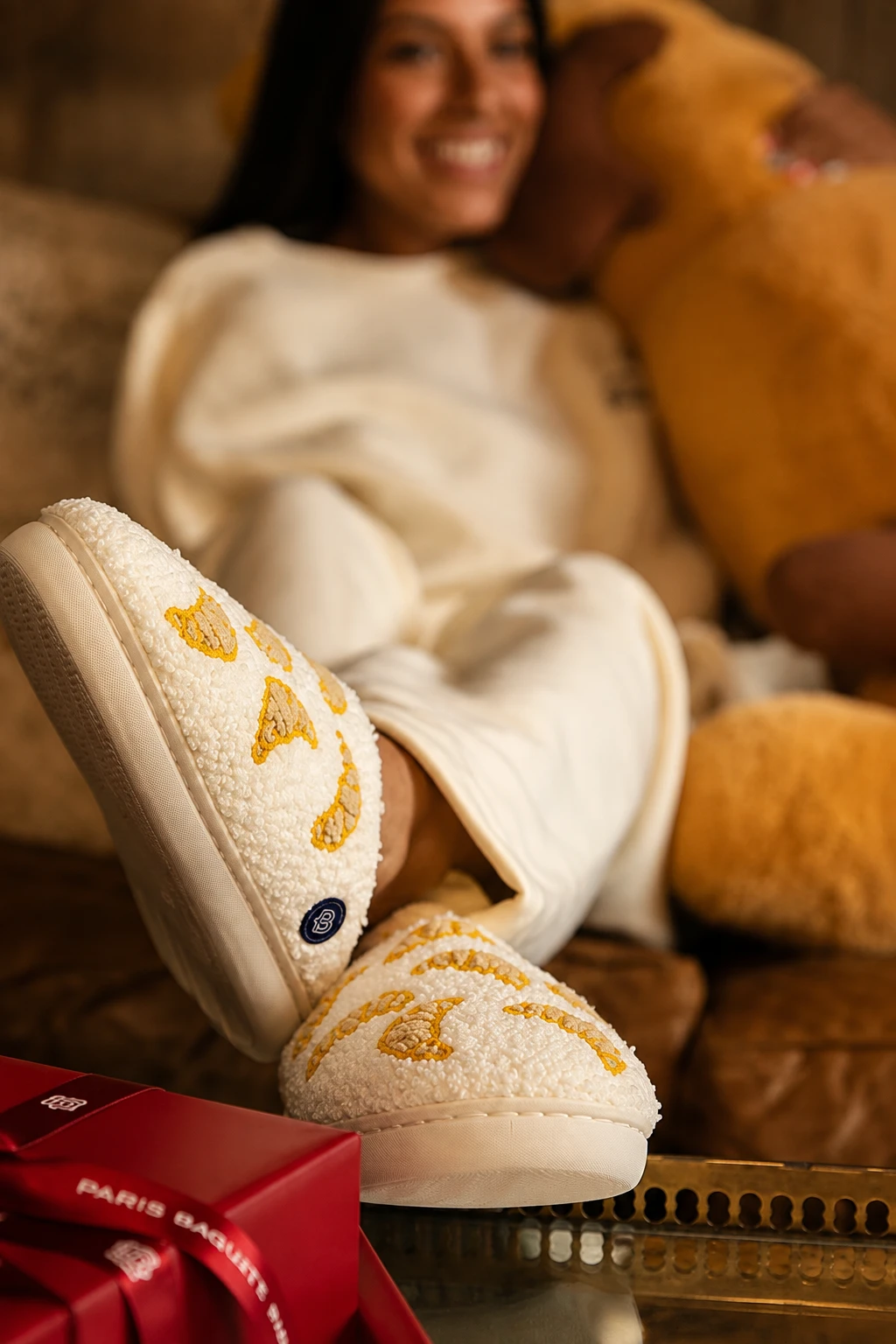 Cream sherpa slippers embroidered with golden croissants and finished with navy Paris Baguette labels.